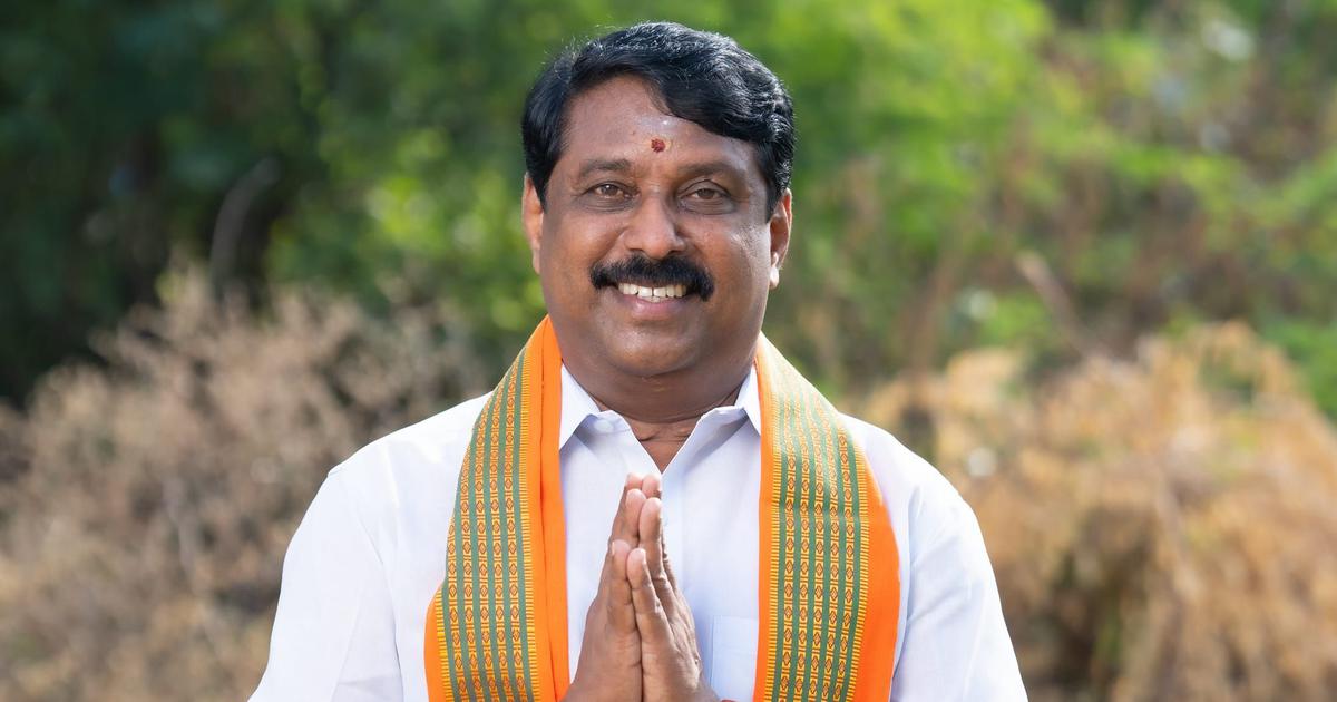 Nainar Nagendran standing outdoors, greeting with folded hands and wearing a party shawl