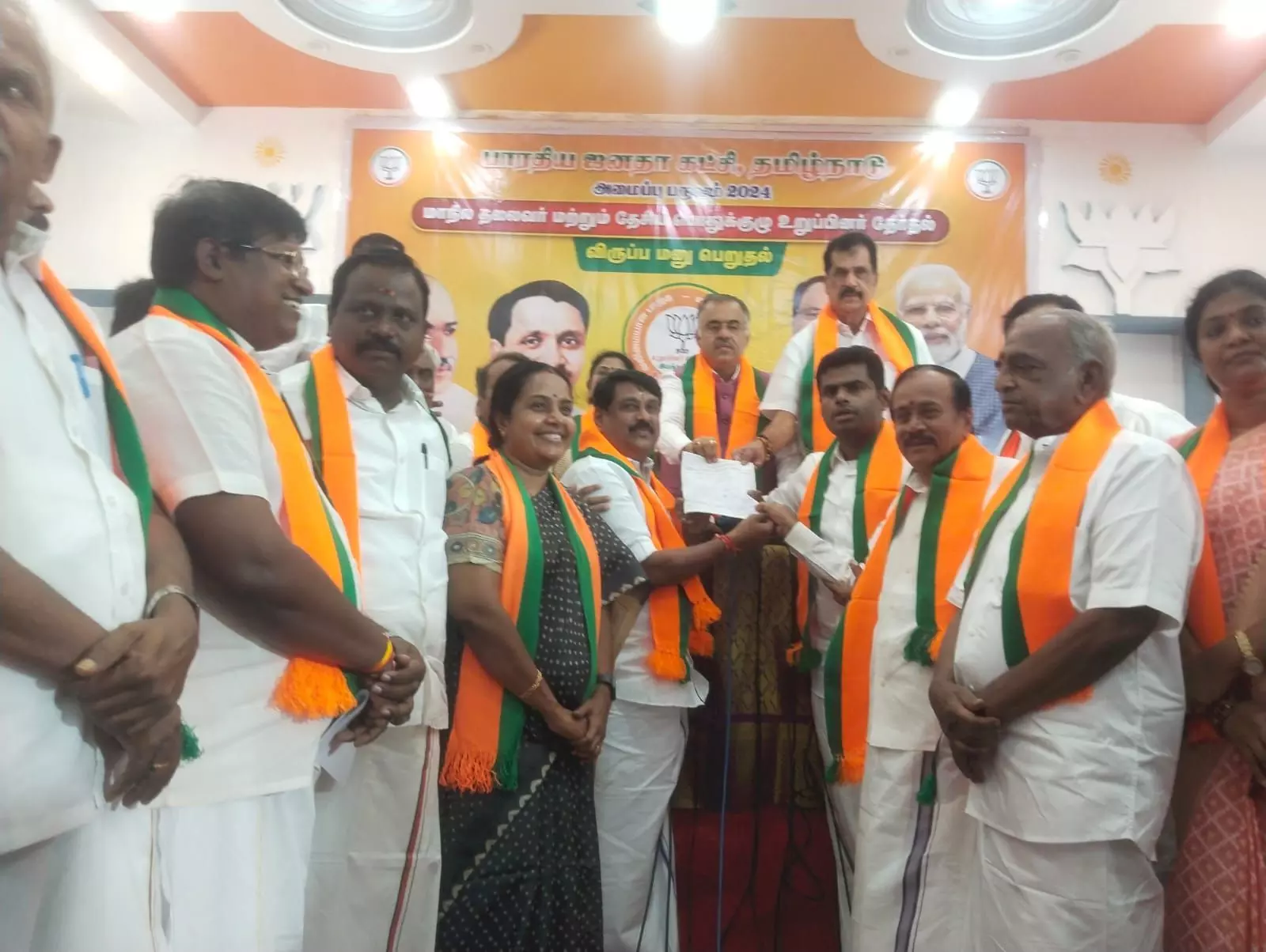 A group of BJP office-bearers in orange party shawls standing together as papers are handed over at a party organisational meeting in Tamil Nadu