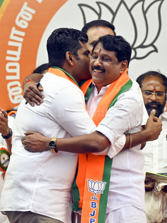 Nainar Nagendran embracing K. Annamalai on stage in front of a party lotus backdrop