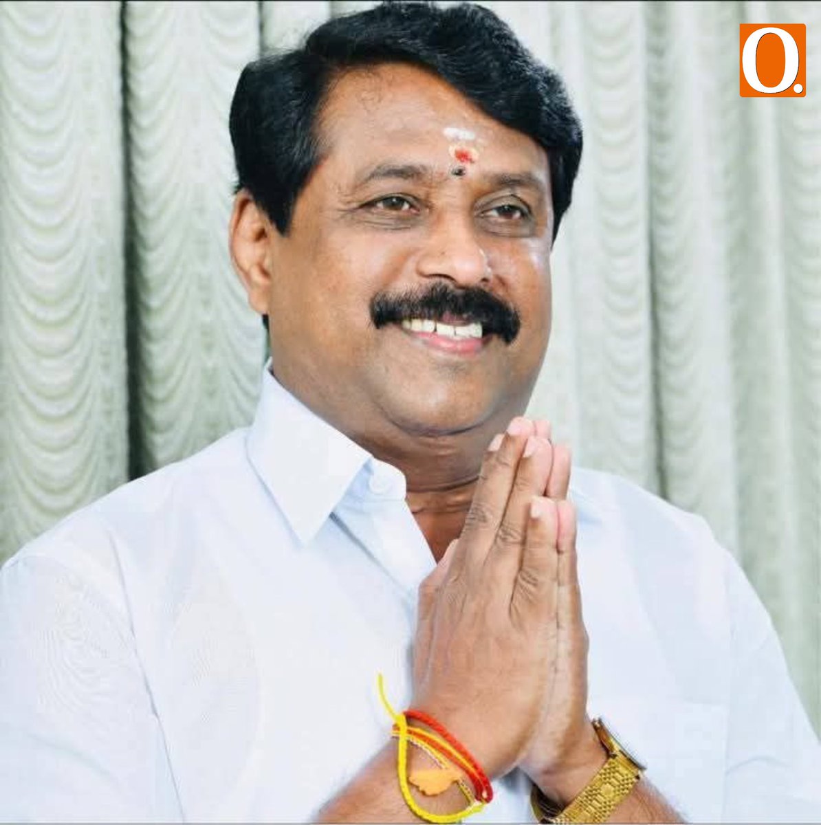 Close portrait of Nainar Nagendran in a white shirt, greeting with folded hands