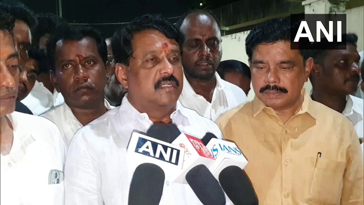 Nainar Nagendran speaking to reporters at night, flanked by party colleagues, with news agency microphones in front of him