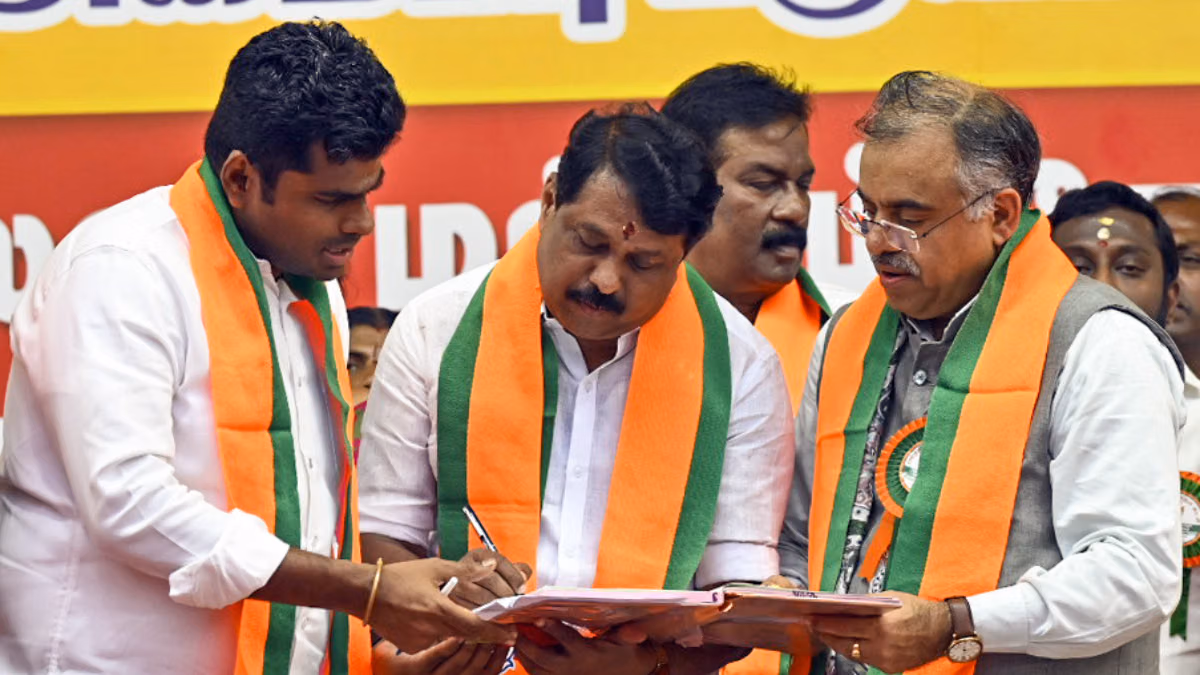 Nainar Nagendran signing papers at a table with K. Annamalai standing beside him and other party officials looking on