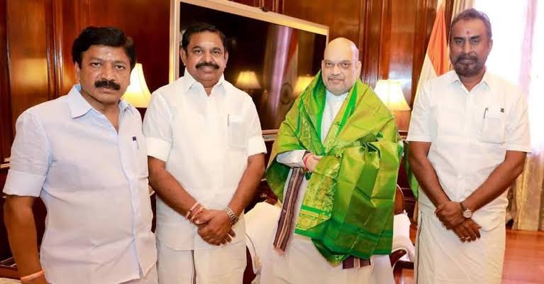 Nainar Nagendran standing with Edappadi K. Palaniswami and Union Home Minister Amit Shah, who wears a green ceremonial shawl, alongside another leader